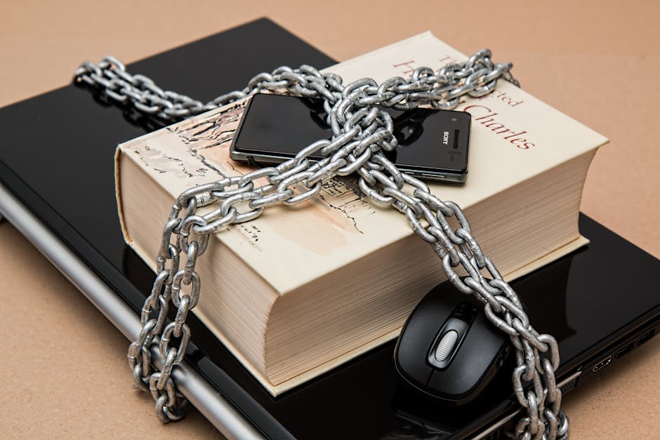 Tutela dati personali e obbligo vaccinale: catena su libro, smartphone e laptop simboleggia la protezione delle informazioni sensibili.