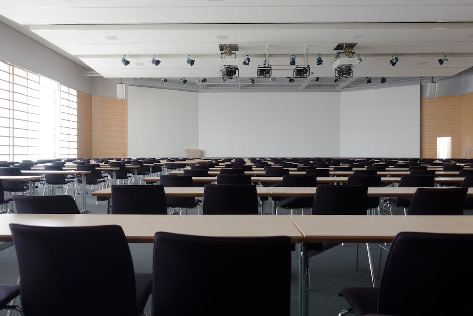 Aula magna vuota con sedie e tavoli, simbolo della mancanza di docenti e posti non assegnati nel sistema scolastico italiano.