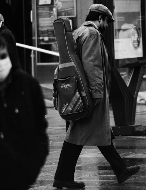 Musicista solitario con custodia di chitarra che cammina per strada, evocando l'emozione e l'influenza della musica nella vita quotidiana.
