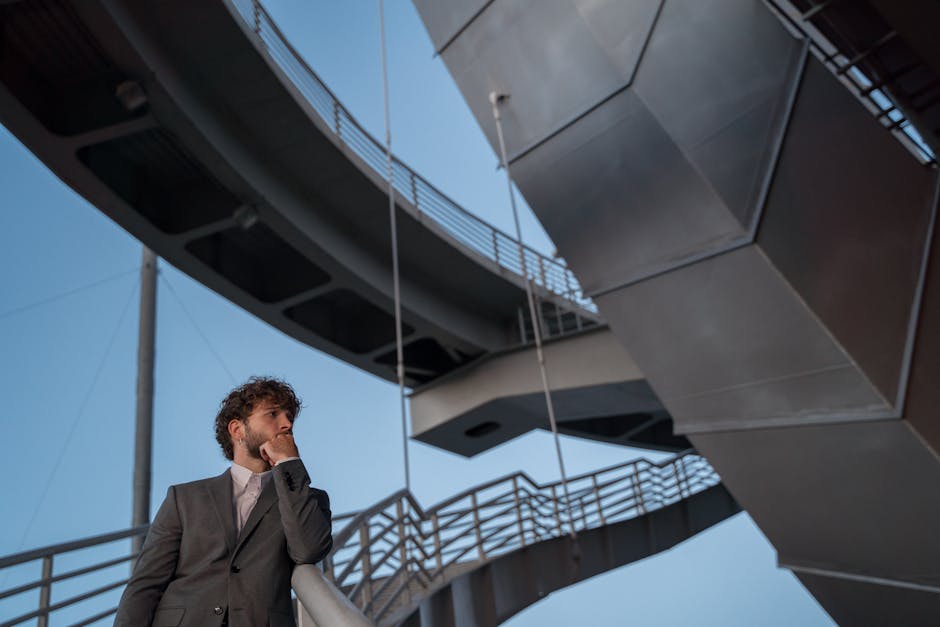 Studente pensieroso in alternanza scuola lavoro riflette sul futuro professionale sotto un ponte moderno con cielo azzurro