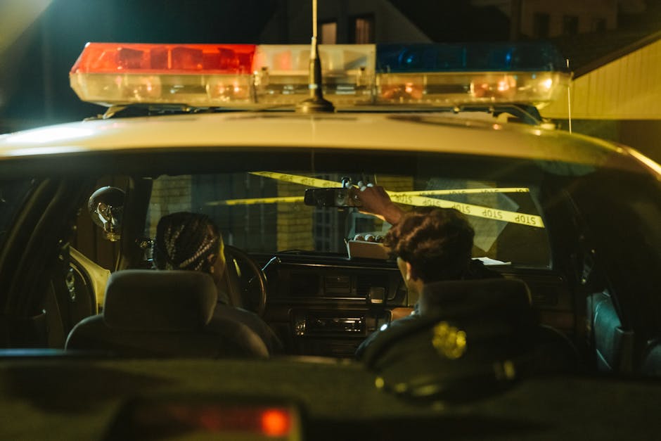 Auto della polizia con agenti di pattuglia notturna: protezione e sicurezza con assicurazione responsabilità civile.