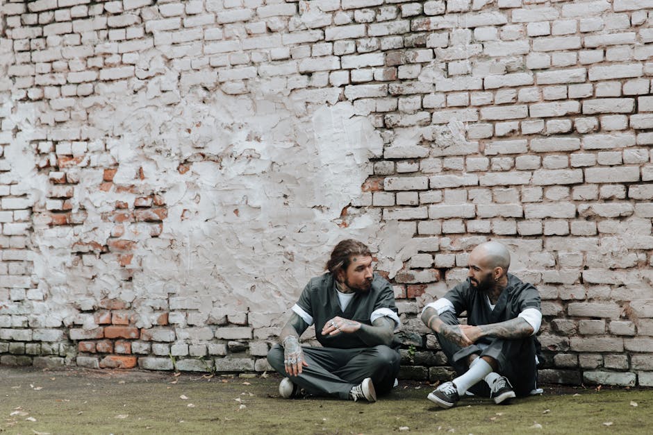 Esercizi di Diritto Penale: Detenuti discutono concetti legali fondamentali davanti a un muro di mattoni, applicando le nozioni apprese.