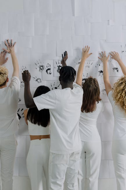 Gruppo di persone che lasciano impronte di mani su carta, simbolo di coinvolgimento della comunità e legami sociali rafforzati.