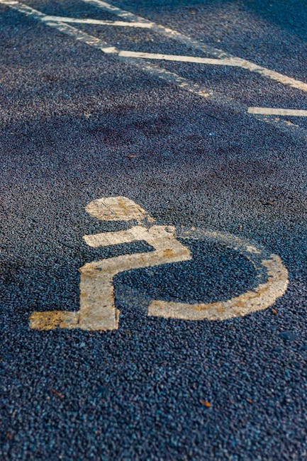 Simbolo di accessibilità per disabili su asfalto blu, area di base per la comprensione dell'inclusione e della progettazione universale.