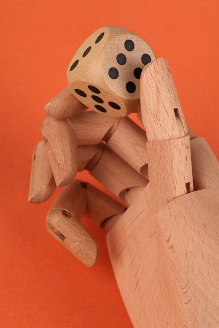 Mano di legno che tiene un dado con il numero sei, simbolo di decisione e rischio nell'articolo Alea Iacta Est.