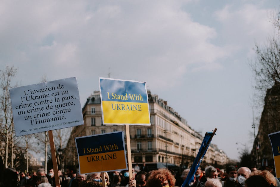 Manifestazione pro Ucraina a Parigi: cartelli con scritte contro la guerra e a sostegno del popolo ucraino, simbolo di conflitto e resilienza.