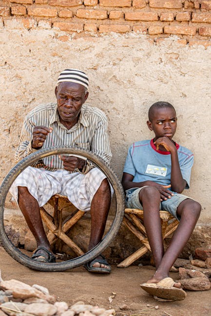 Uomo anziano africano ripara una gomma di bicicletta con un ragazzo, competenze informali e trasmissione del sapere intergenerazionale