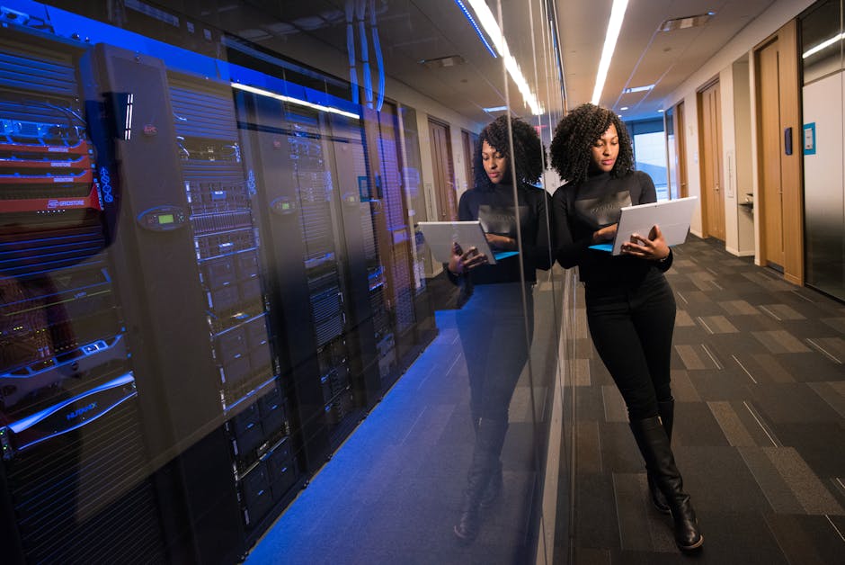 Donna con tablet in data center, riflesso dei server. Sostenibilità e accordi tecnologici per i data center negli Stati Uniti.