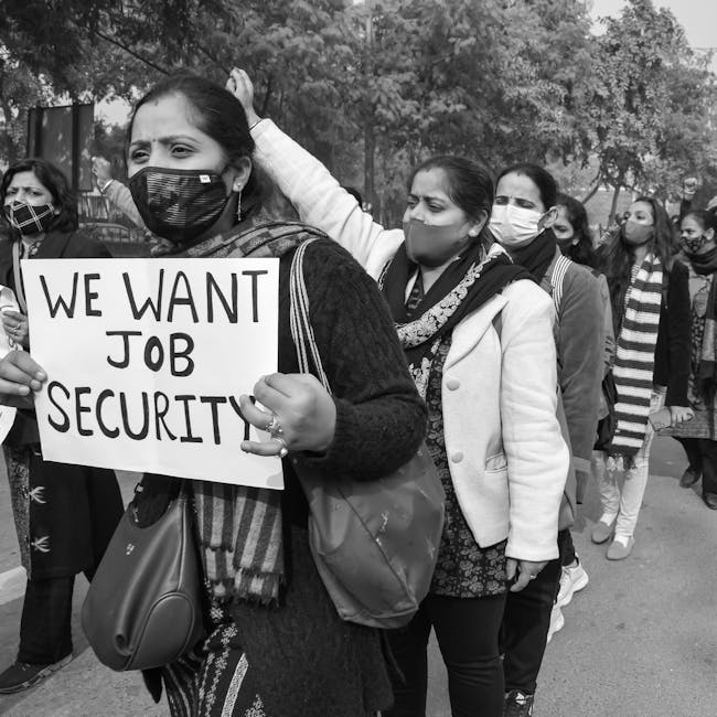 Manifestazione per la sicurezza del lavoro: donne in marcia con cartello 'We want job security' per rilancio lavoro e sicurezza.
