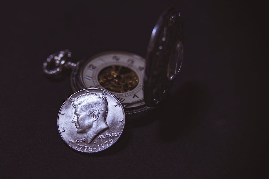 Moneta commemorativa di John F. Kennedy e orologio da taschino: simboli del tempo e dell'eredità presidenziale americana.