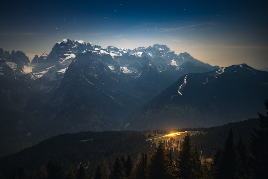 Paesaggio montano notturno con cime innevate e luce dorata, ideale per illustrare la formula del vertice parabola e la sua applicazione pratica.