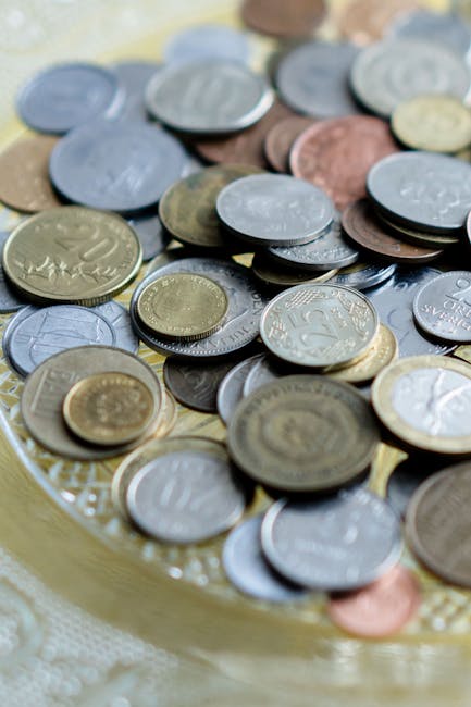 Monete di diverse valute su un piatto, simbolo della politica monetaria e dell'economia globale