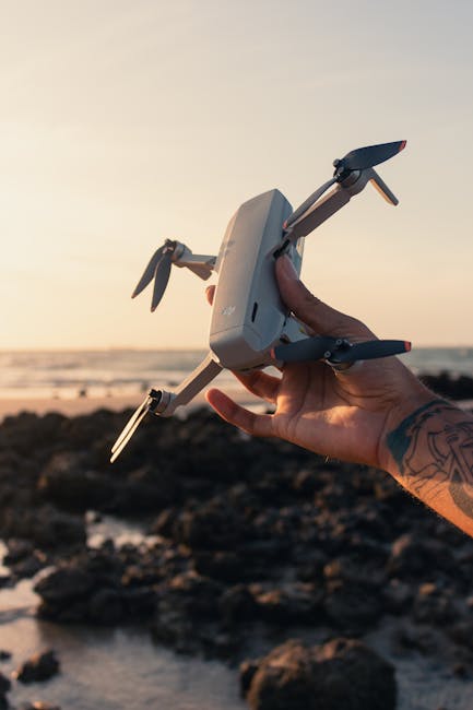 Drone DJI Mini 2 in mano con sfondo spiaggia al tramonto: esplora l'innovazione dell'Aeronautica a Pozzuoli e la passione per il volo.