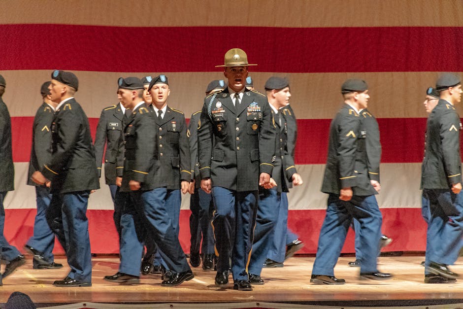 Cerimonia di allievi delle accademie militari americane in uniforme di gala con bandiera USA sullo sfondo, formazione leader.