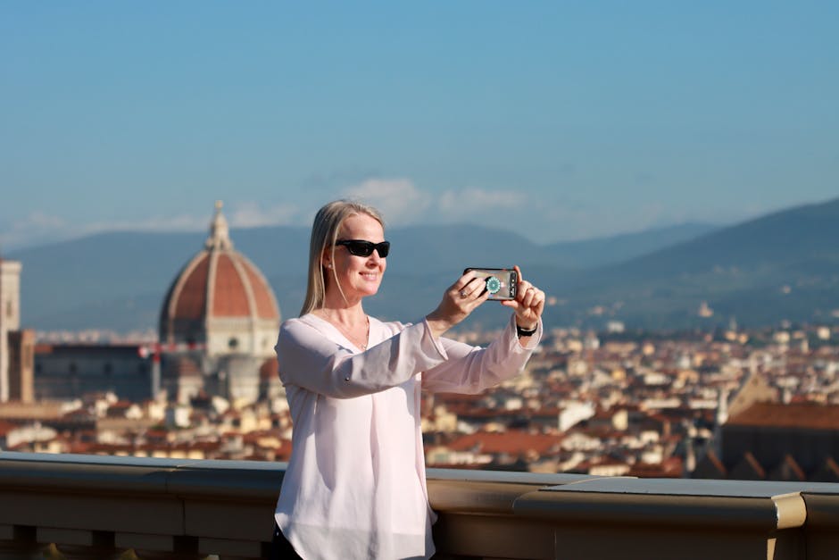 Donna bionda fotografa Firenze con smartphone: un poco di bellezza italiana catturata in un'immagine per l'articolo sulla lingua.