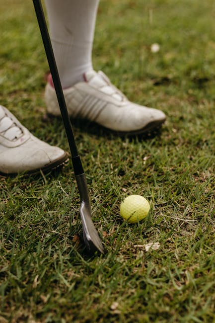 Preparazione al tiro nel golf: mazza, pallina e scarpe da golf sull'erba, metafora di precisione e preparazione per il corso di fisica a Tor Vergata