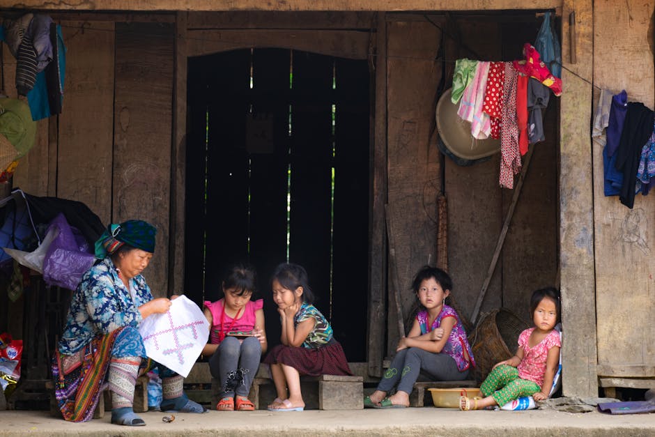 Famiglia indigena seduta davanti a casa in legno: nonna, nipoti e il rischio di allontanamento per decisione del Tribunale dei Minori.