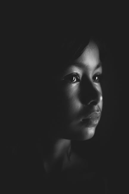 Ritratto in bianco e nero di giovane volto femminile, espressione pensierosa, ombre profonde che evocano riflessioni sugli stereotipi di genere