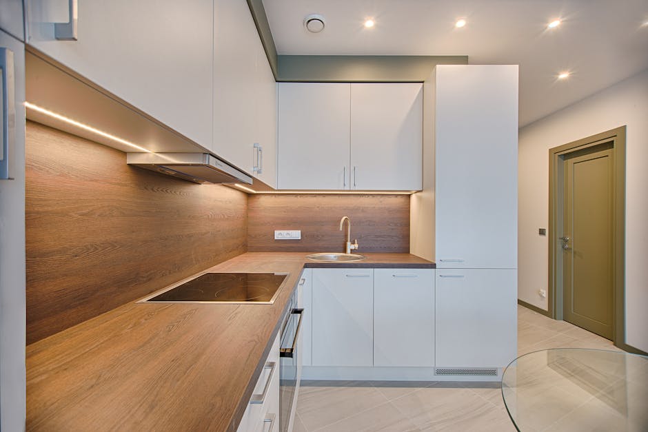 Cucina moderna con piano in legno e mobili bianchi illuminati, design elegante e funzionale per la preparazione dei cibi.