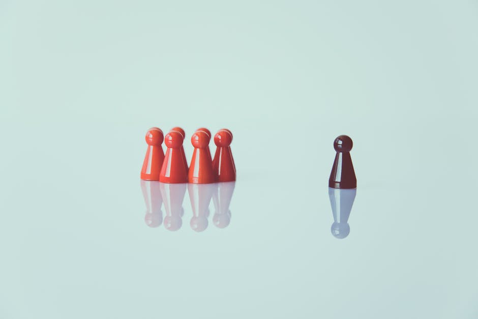 Pedine rosse in gruppo e pedina marrone isolata: metafora di inclusione e giochi di gruppo unici per bambini