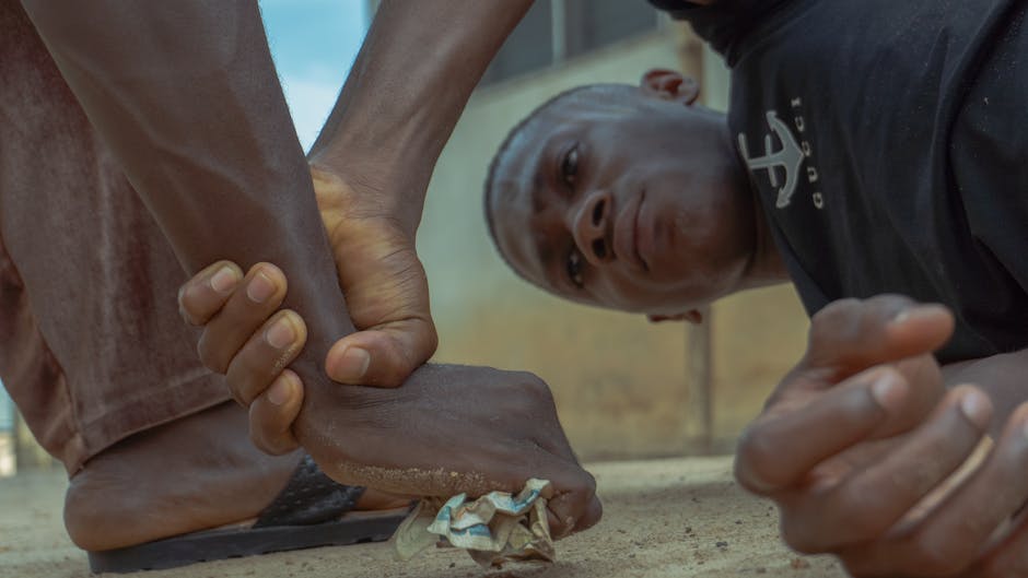Uomo con espressione di dolore, piede schiacciato da un altro uomo, simboleggia la tensione emotiva e fisica nell'articolo.