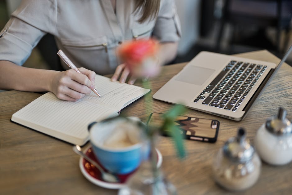 Donna prende appunti su agenda accanto a laptop e caffè, webinar Ministero pagamenti digitali: guida e approfondimento