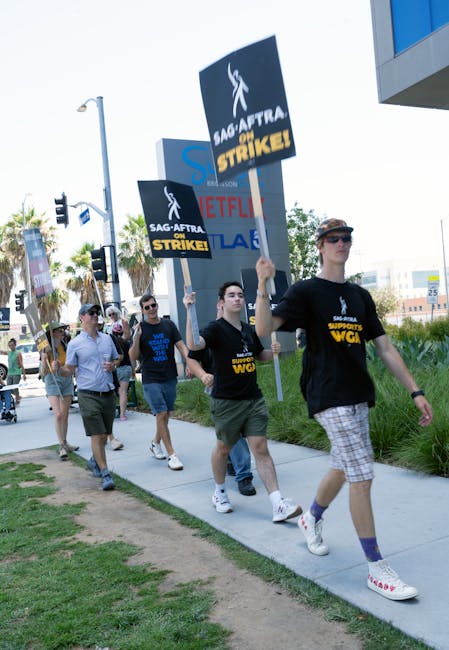 Sciopero a scuola: manifestanti con cartelli SAG-AFTRA e WGA contro Netflix e altri, in protesta per salari e condizioni di lavoro.