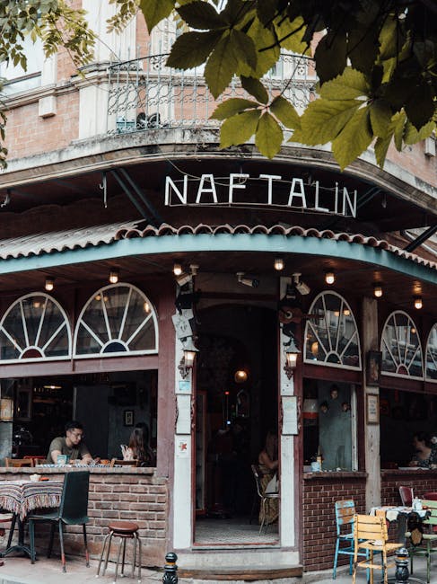 Tavoli e sedie regolabili in un accogliente caffè con insegna Naftalin, per un benessere ottimale durante il lavoro o il relax.