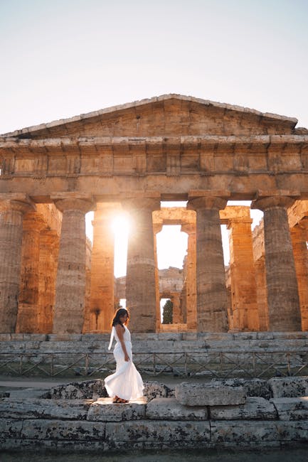 Donna in abito bianco davanti al Tempio di Nettuno a Paestum, sito archeologico vicino Ravenna, viaggio nella storia e cultura