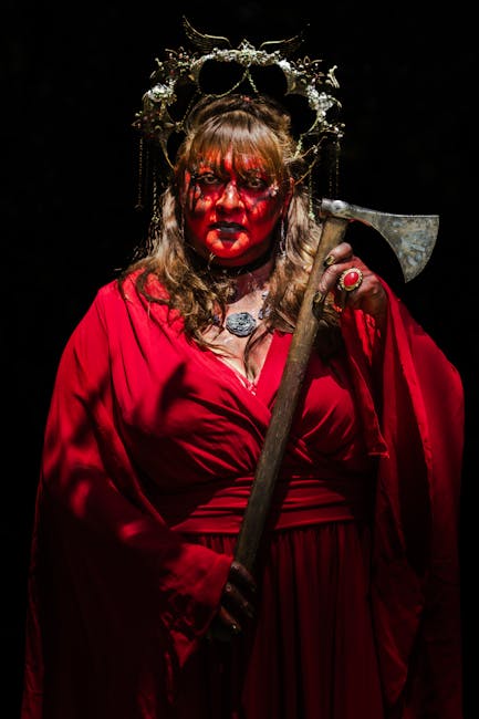Ritratto di donna vestita di rosso con trucco rosso e corona, che evoca Maria la Sanguinaria e il terrore del potere regale.