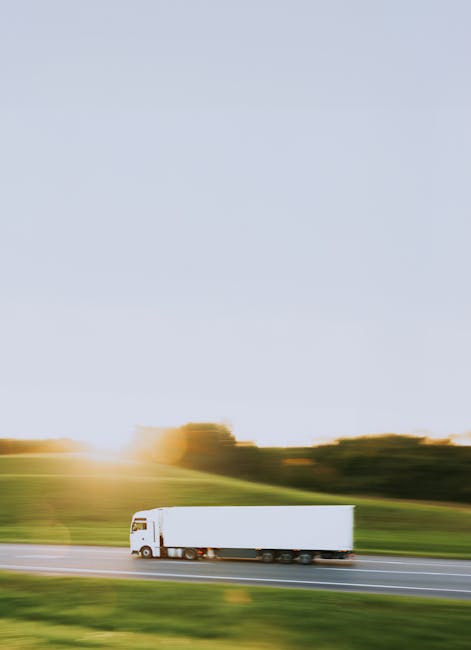 Trasporto di prodotti agricoli: un camion bianco su strada tra campi verdi, eco delle Georgiche di Virgilio e del lavoro nei campi.