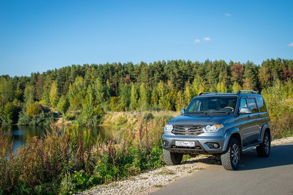 SUV grigio su strada di campagna con lago e bosco sullo sfondo, ideale per chi cerca informazioni sulla patente B e auto