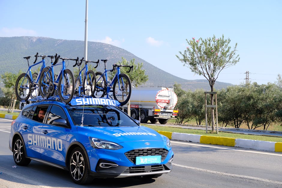 Auto blu con biciclette sul tetto, sponsor Shimano, utile per articoli su formazione e specializzazione sostegno scolastico.