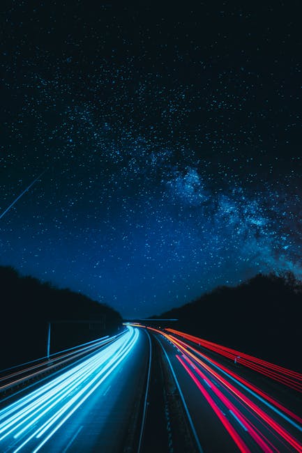 Via lattea sopra autostrada illuminata dalle scie luminose delle auto, un viaggio cosmico tra cielo e terra nell'universo.
