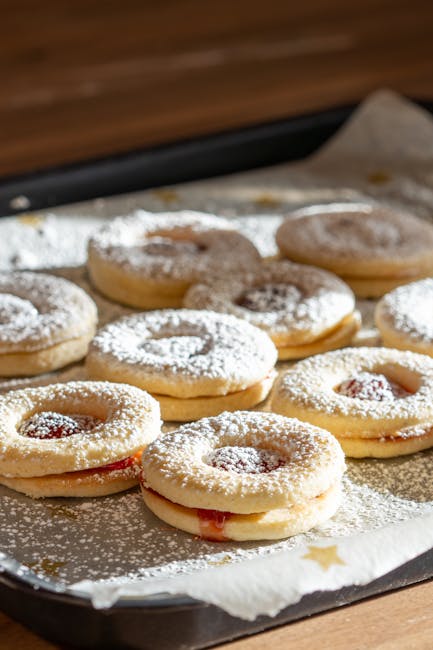 Biscotti Linzer con marmellata e zucchero a velo su teglia, simbolo di tradizione e innovazione nella panificazione artigianale.