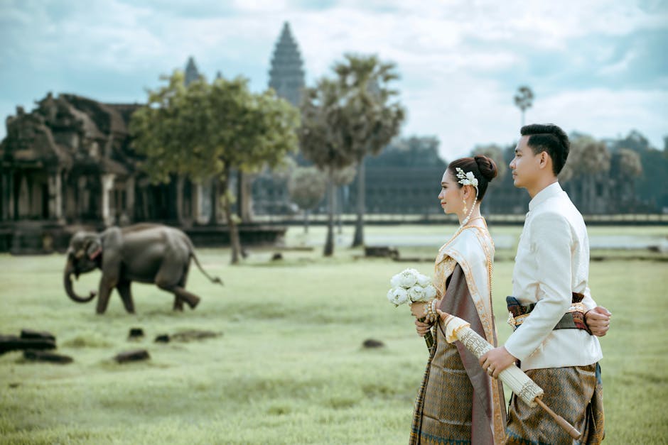 Coppia in abiti tradizionali cambogiani con elefante sullo sfondo, Angkor Wat. Istruzione e cultura a confronto.