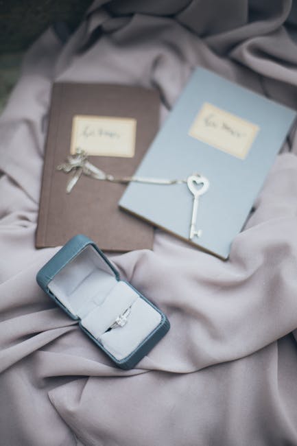 Anello di fidanzamento in scatola blu con libri e chiave a cuore, metafora della preparazione all'Esame Unico e del futuro.