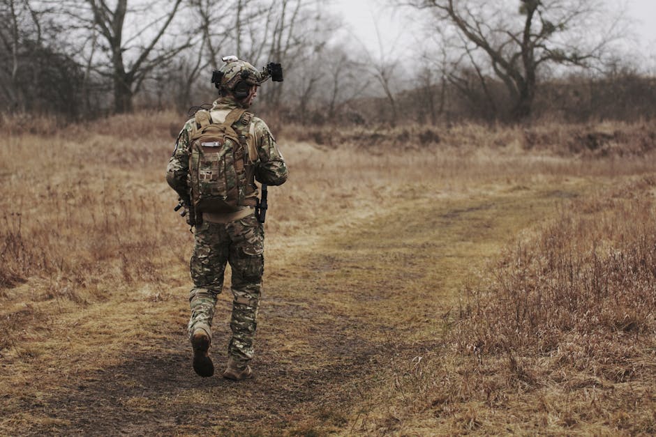 Soldato in uniforme mimetica durante un addestramento militare unico, cammina su un sentiero in un campo desolato, parte dell'articolo sulle sfide e vantaggi.