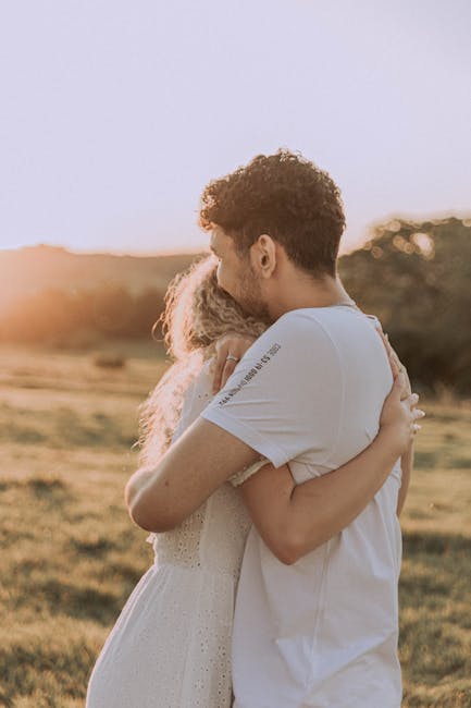 Giovane coppia si abbraccia al tramonto, simbolo di supporto e sollievo dalla stanchezza cronica e dal carico di cura femminile.
