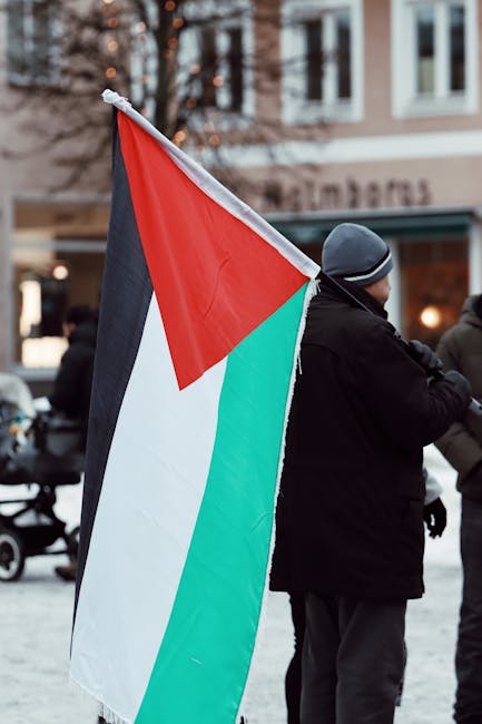 Manifestante con bandiera palestinese durante una protesta per la pace in Palestina, simbolo di solidarietà e sostegno alla causa.