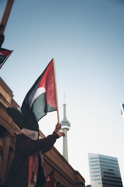 Manifestazione a Toronto per la Global Sumud Flotilla con bandiera palestinese e CN Tower sullo sfondo, simbolo di solidarietà internazionale.