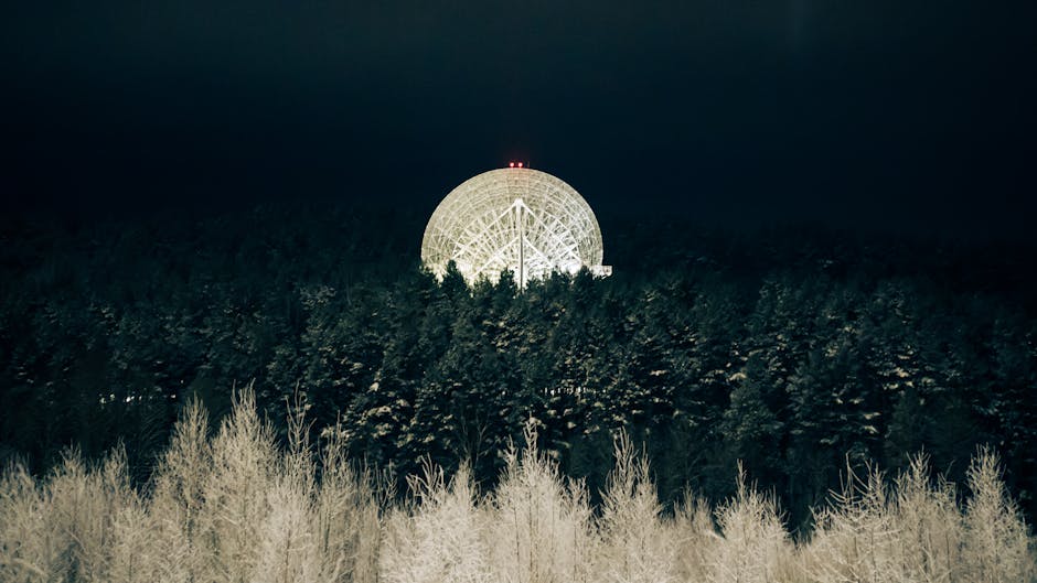 Antenna parabolica illuminata di notte, simbolo di ricerca scientifica per la Notte Europea dei Ricercatori
