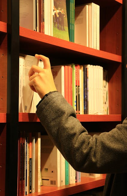Mano che prende un libro da una libreria piena di volumi per studio e approfondimento concetti matematici come il volume del cilindro