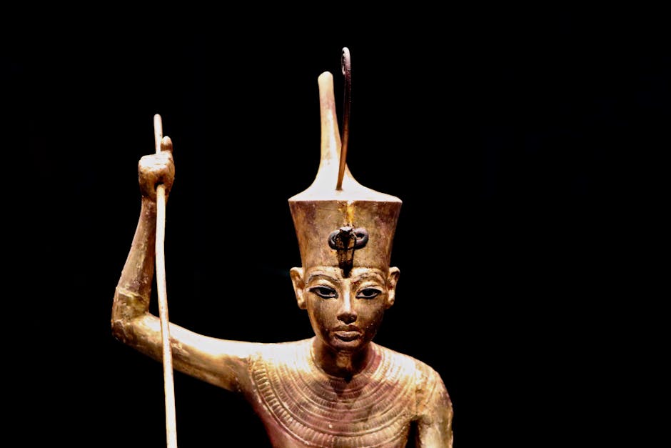 Statua dorata di faraone egizio con scettro, simbolo di potere e regalità, evocativa delle figure leggendarie come Romolo.