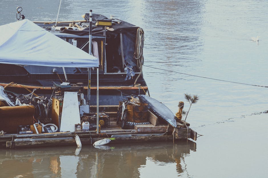 Immagine di una casa galleggiante sul fiume, esempio di vita alternativa e scelte uniche nell'avventura Enea. Dettagli della struttura e dell'ambiente circostante.