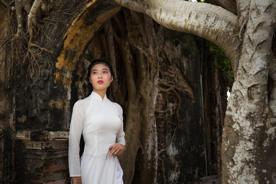 Donna in abito tradizionale vietnamita Ao Dai, evocazione di antiche tradizioni e radici culturali, sfondo di architettura storica