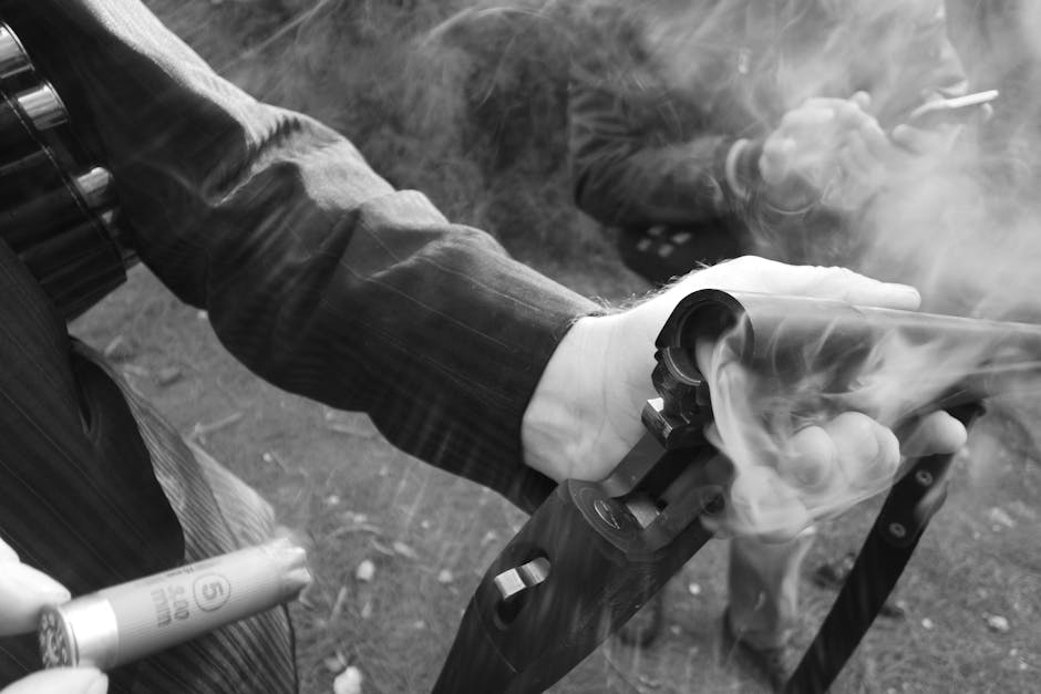 Uomo con fucile a canne mozze fumante e cartuccia in mano, potenziale pericolo legato a esplosivi artigianali e sicurezza