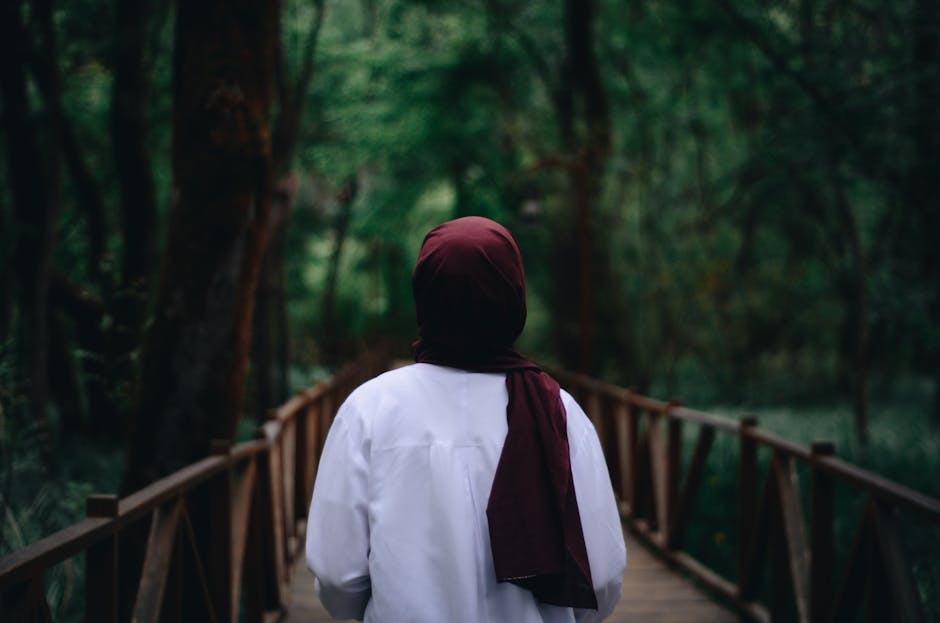 Donna con hijab bordeaux su ponte di legno, esplorando la diversità culturale nei laboratori di antropologia culturale.