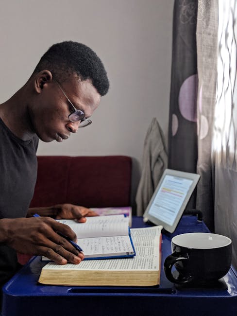 Studente concentrato studia con libro, quaderno e tablet, esempio di apprendimento ibrido e sinergia tra pedagogia e tecnologia
