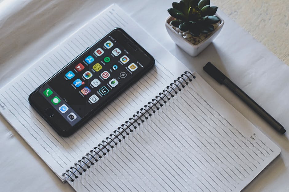 Smartphone con app social su quaderno a righe e penna, riflessione sull'importanza della scrittura a mano nell'era digitale.